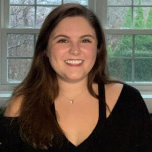 Abby Hanssen smiling in a black shirt in front of a window
